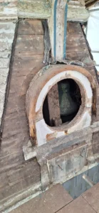 photo of the tower with the grill removed revealing the bell inside. It shows the date plaque has been removed